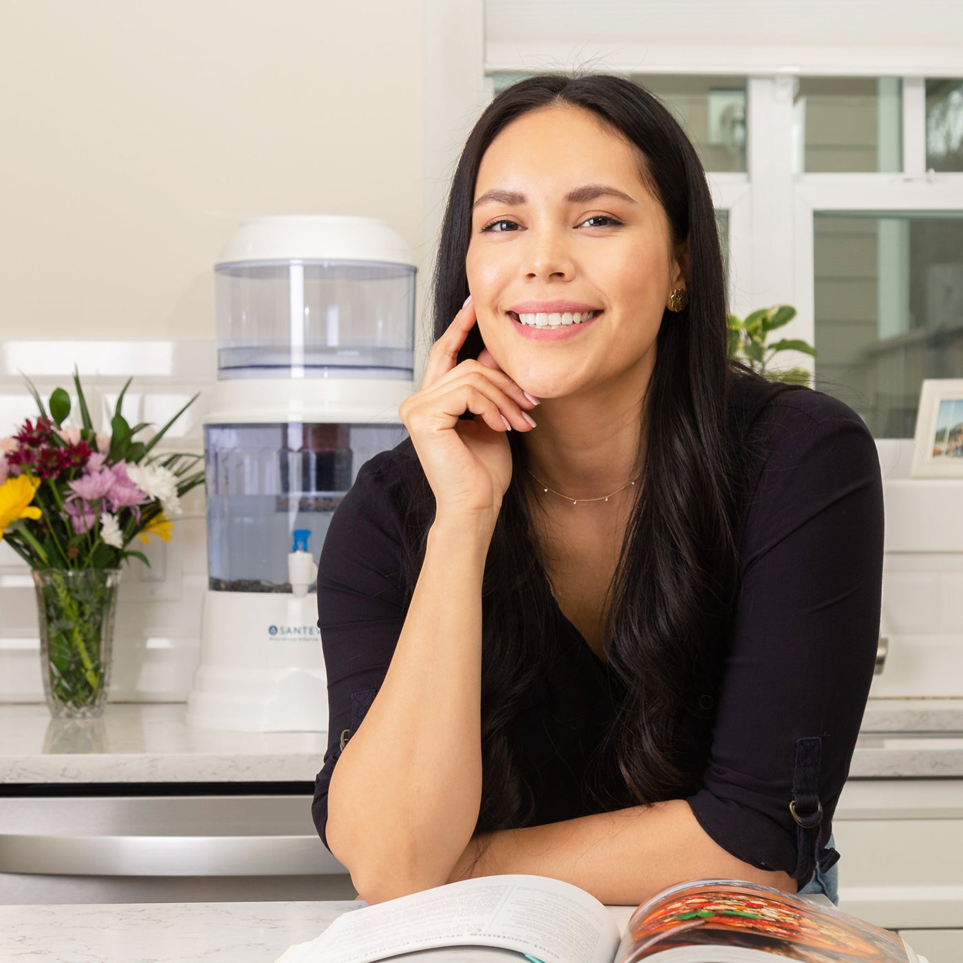 A woman reading a healthy cooking book and smiling in front of her Santevia Gravity Water System#filter-type_fluoride-removal-filter