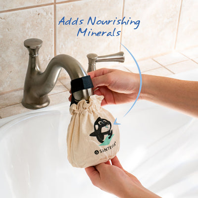 A Santevia Bath Filter hanging on a bath tub faucet with an arrow highlighting that it adds nourishing minerals.